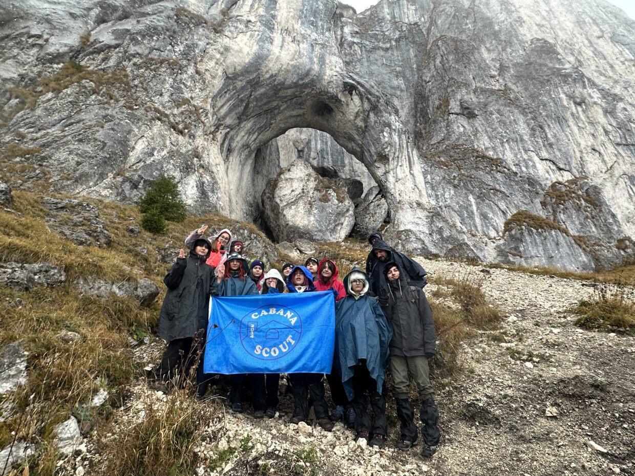 Exploratori Cabana Scout cu steagul centrului, sub arcada de piatră din Piatra Craiului